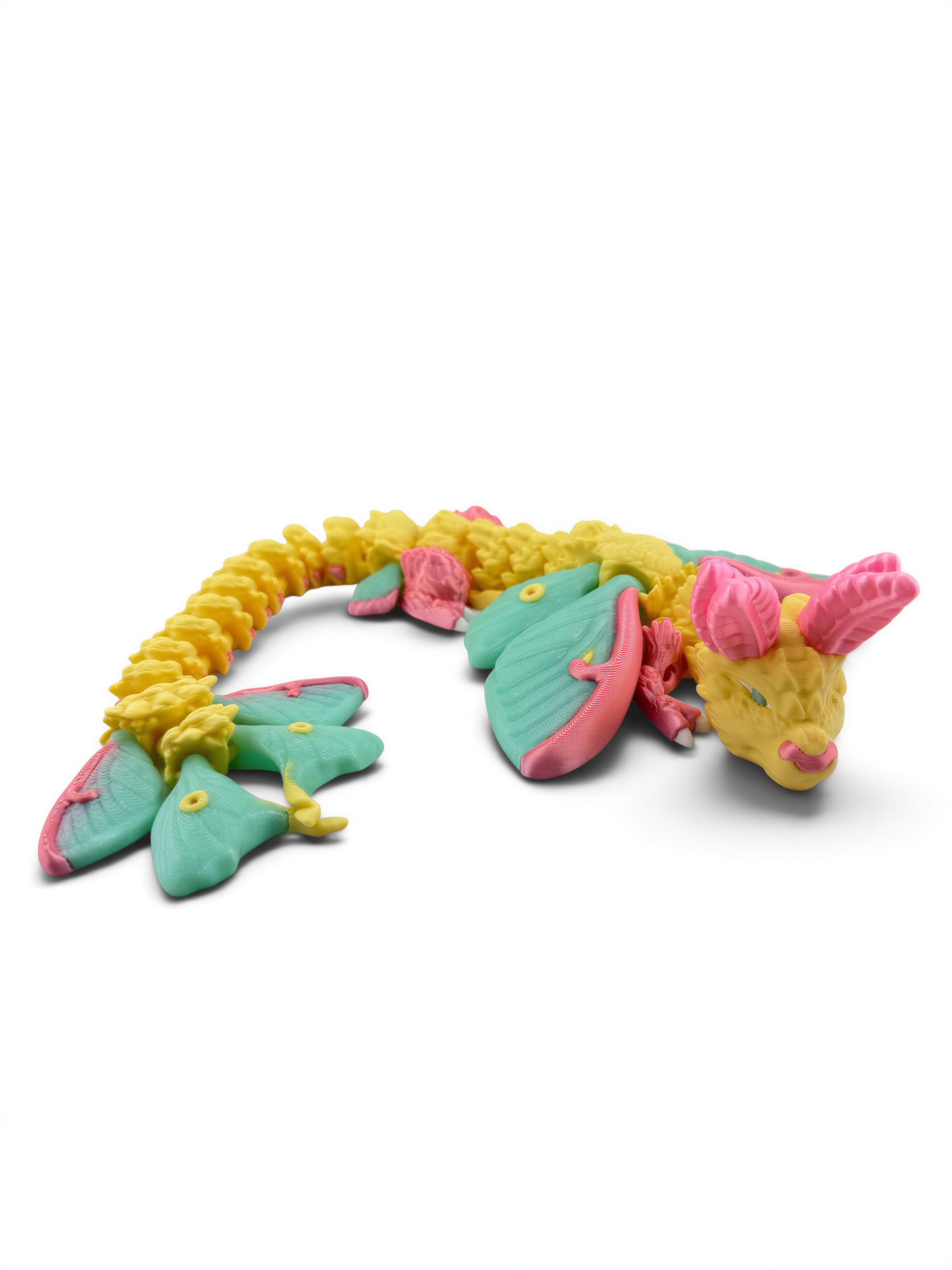 A colorful toy dragon with yellow scales, green wings, and pink accents is shown against a white background.