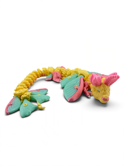 A colorful toy dragon with yellow scales, green wings, and pink accents is shown against a white background.