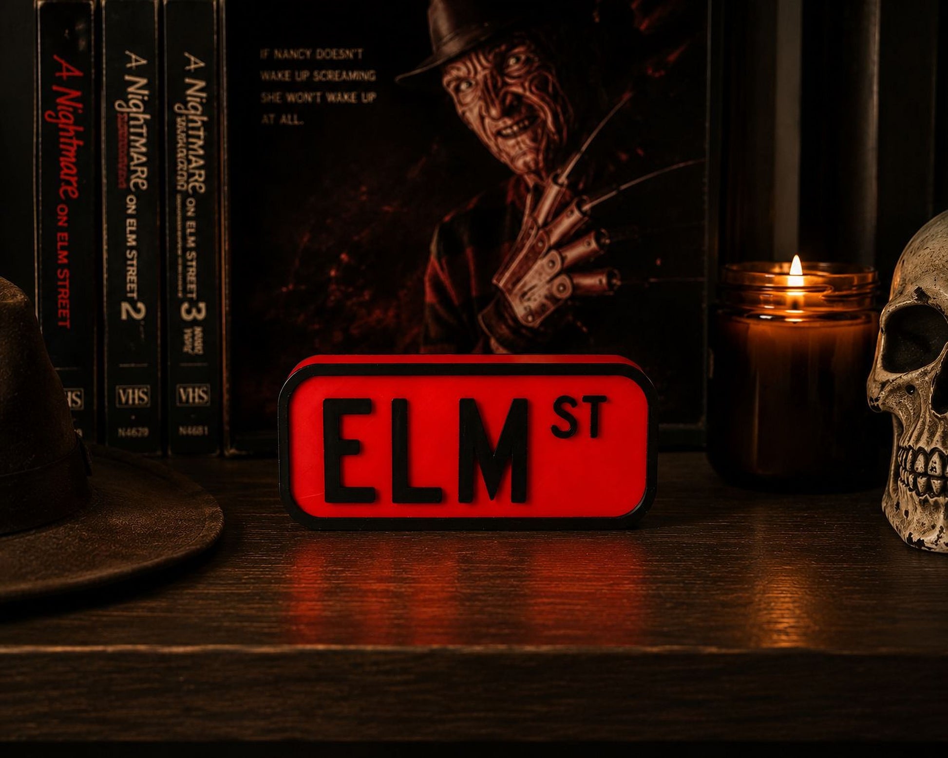 a shelf with various items, including a skull, a candle, a book, and a red sign that says "ELM ST".