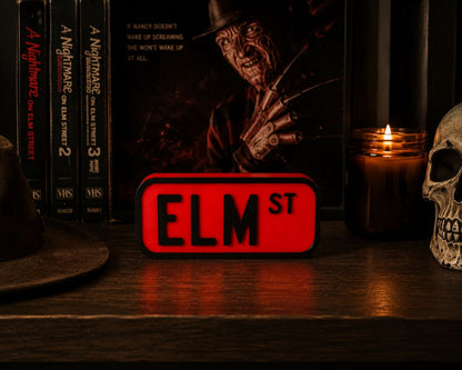 a shelf with various items, including a skull, a candle, a book, and a red sign that says "ELM ST".