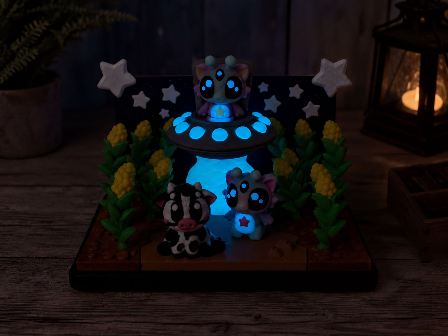 A whimsical scene featuring a toy alien, a cow, and a cat, all illuminated by blue lights, set against a backdrop of stars and plants.