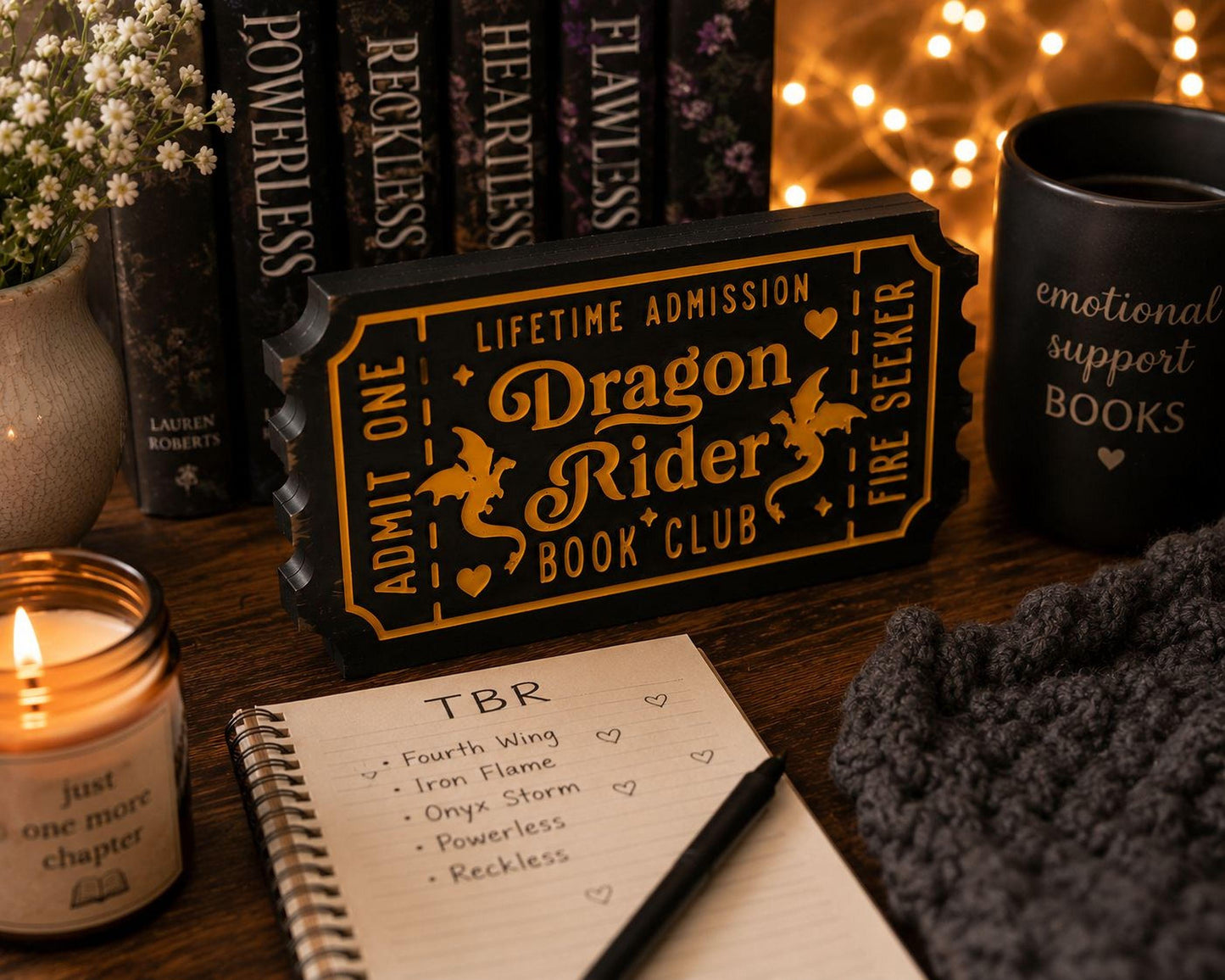a cozy scene with a candle, a notebook, and a mug, all arranged on a wooden surface.