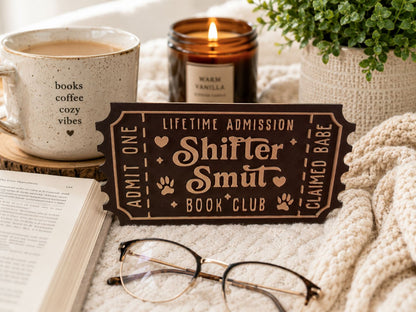 a cozy scene with a book, a pair of glasses, a candle, and a ticket for a book club.