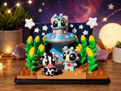A whimsical display featuring three colorful, cartoonish animal figurines set against a starry night sky backdrop, with a spaceship and other celestial elements.