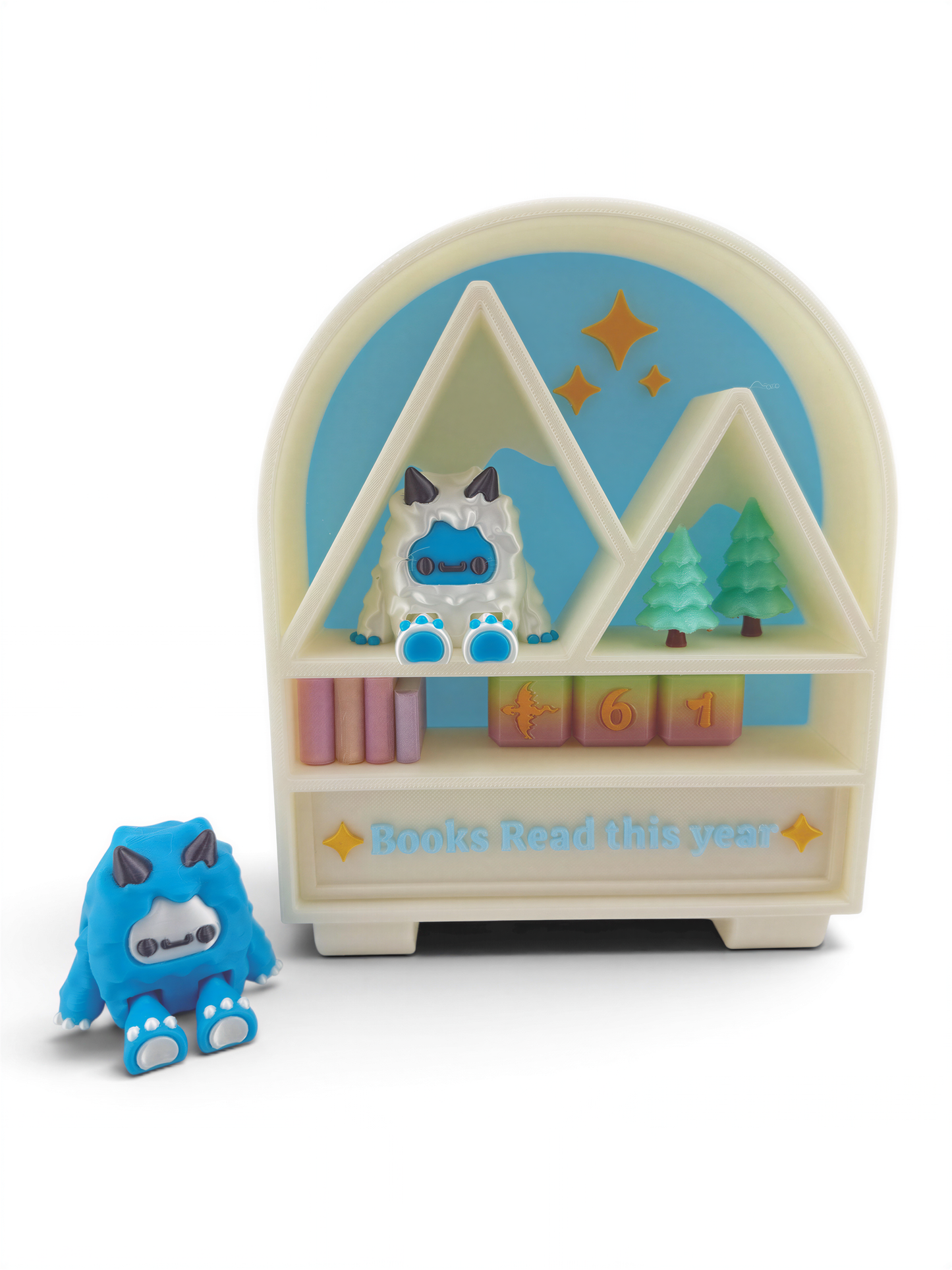 A toy shelf with a blue monster figurine sitting on it, and a small blue monster figurine next to it. The shelf has a sign that says "Books Read this year".