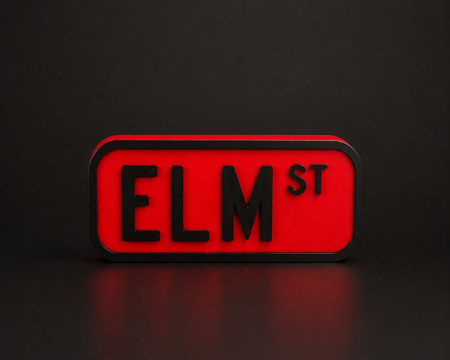A red rectangular sign with the word "ELM ST" in black letters.