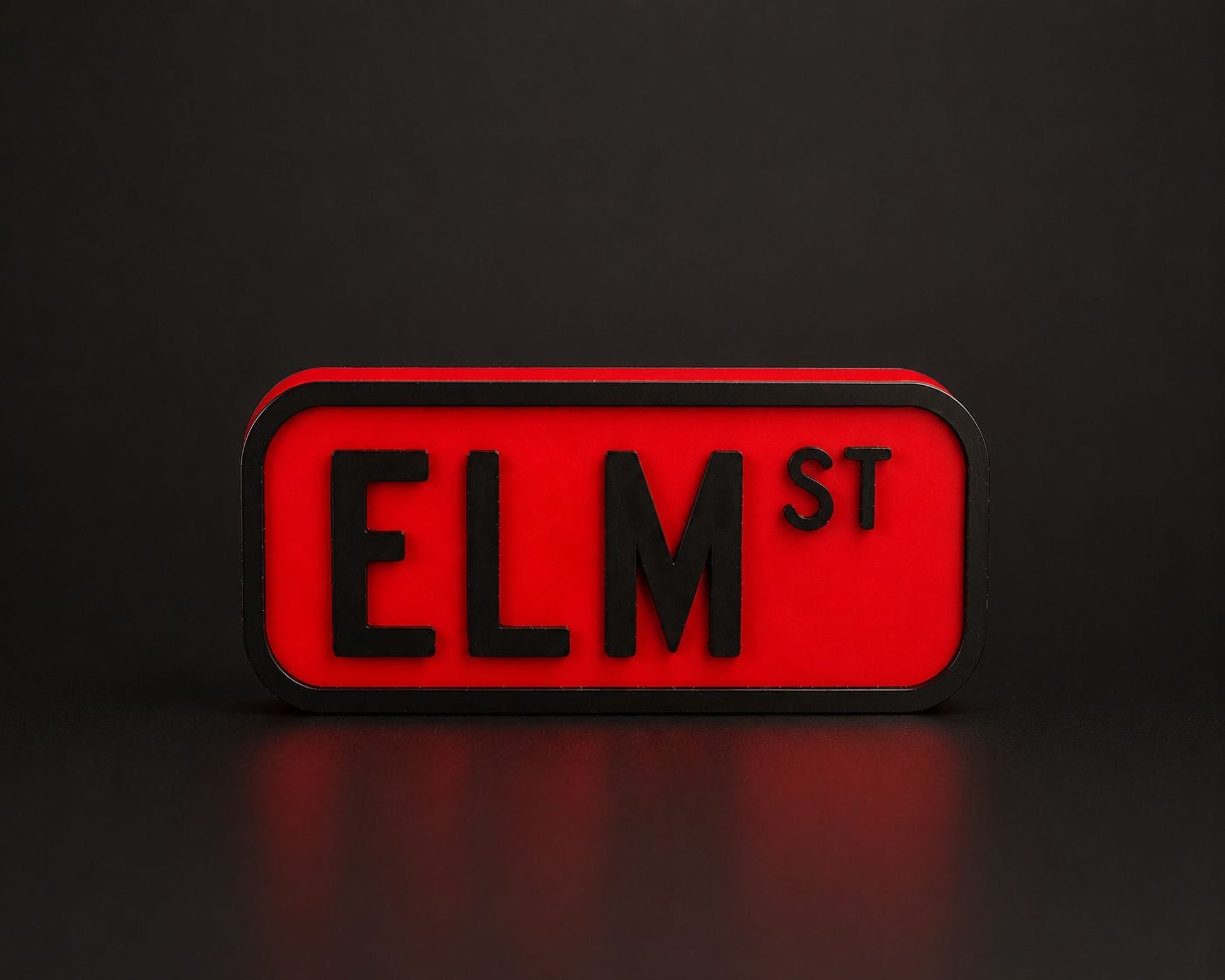 A red rectangular sign with the word "ELM ST" in black letters.